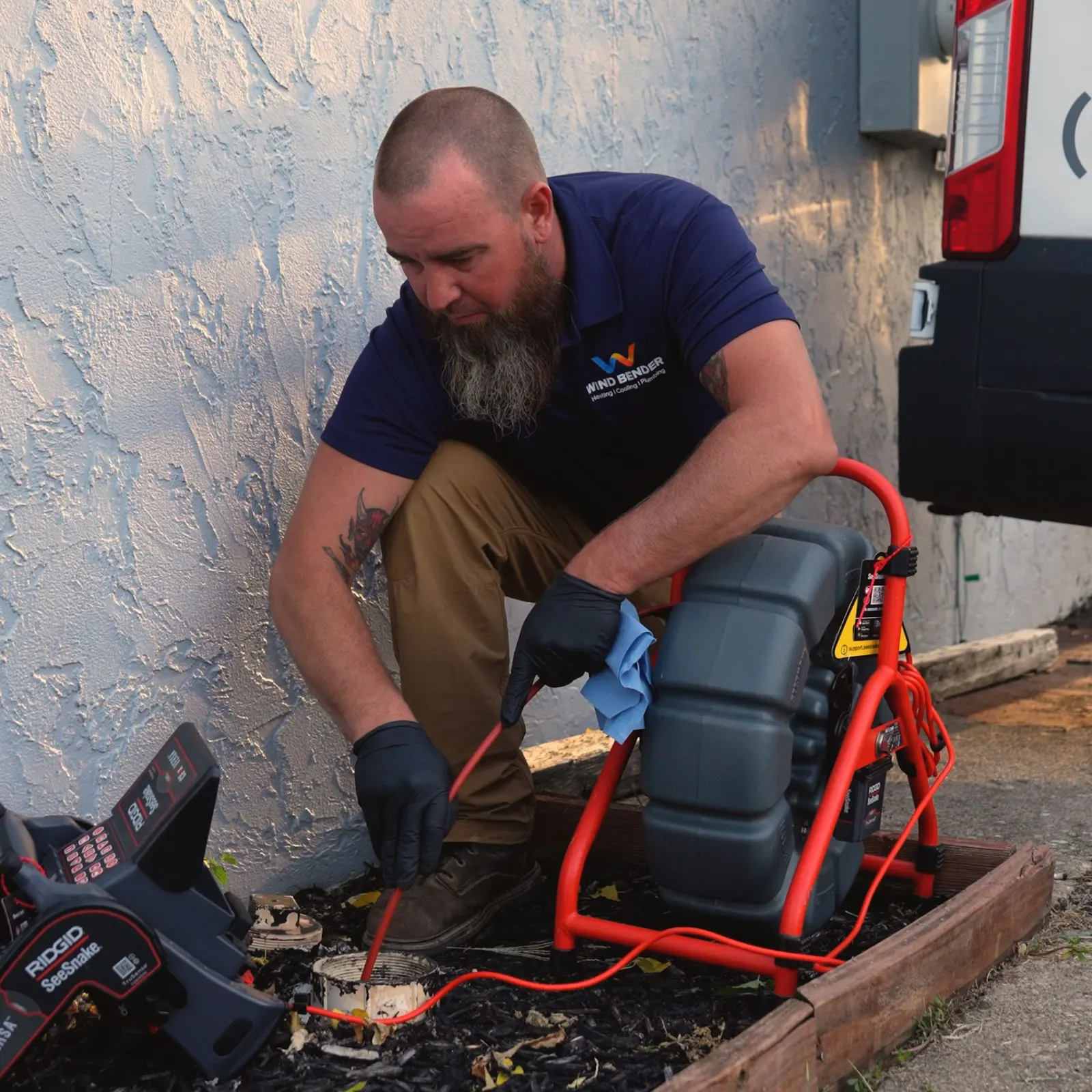A Wind Bender plumber running a drain camera outside a customer's home